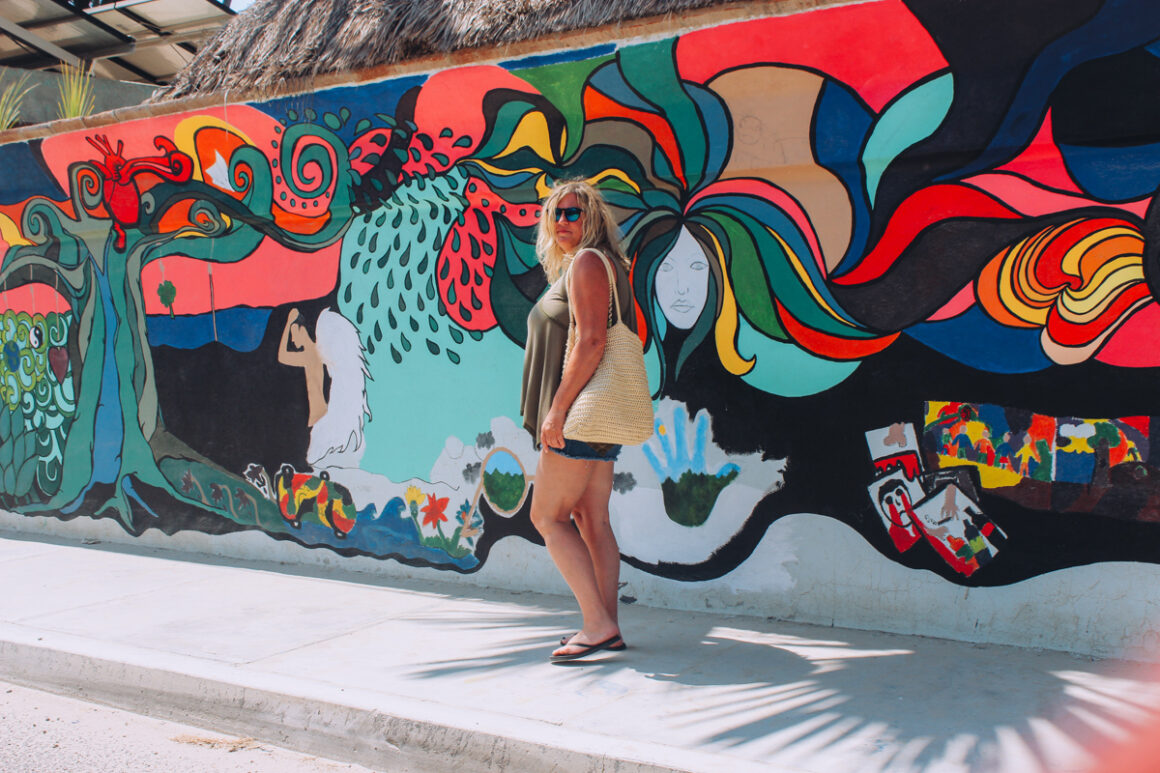 a girl walking in front of a mural in Todos Santos