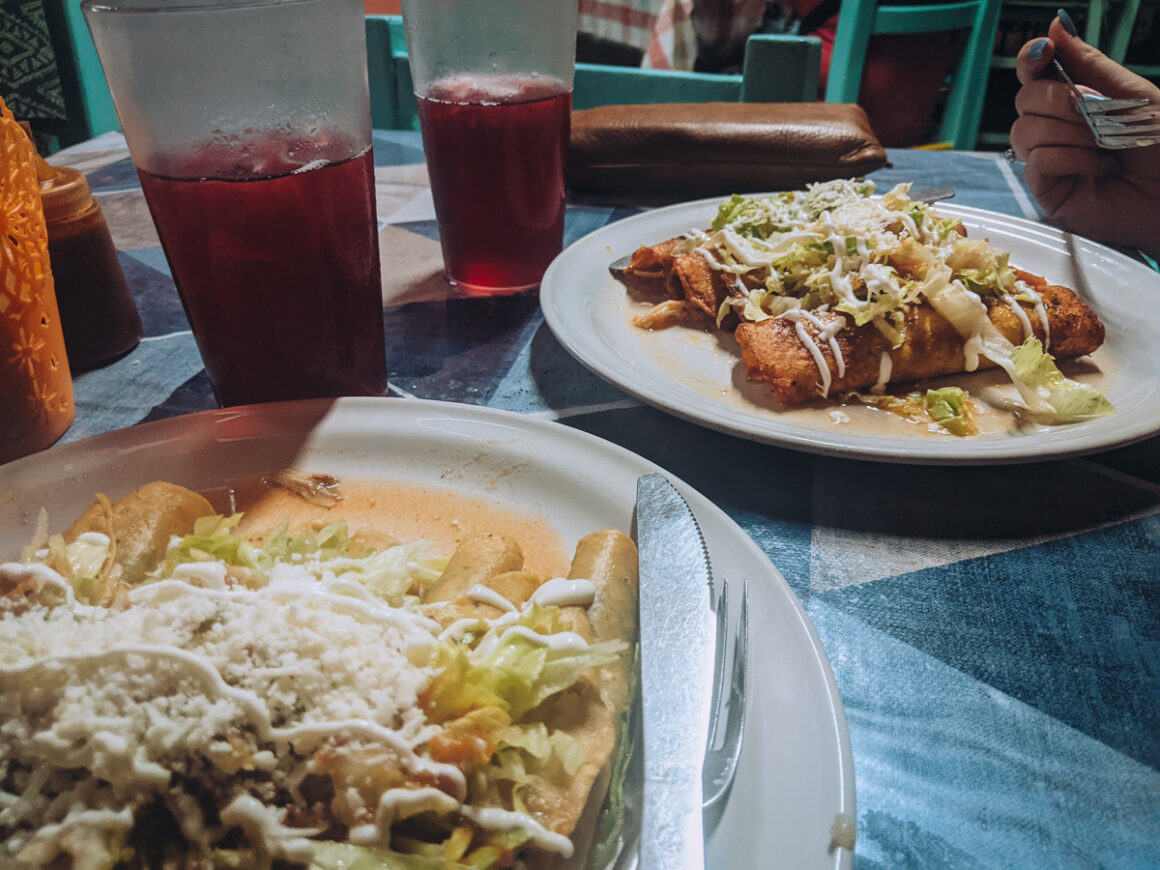 Tacos dorados and enchiladas on table with green chairs at el Campanario one of the best restaurants where to eat in Puerto Vallarta, Mexico