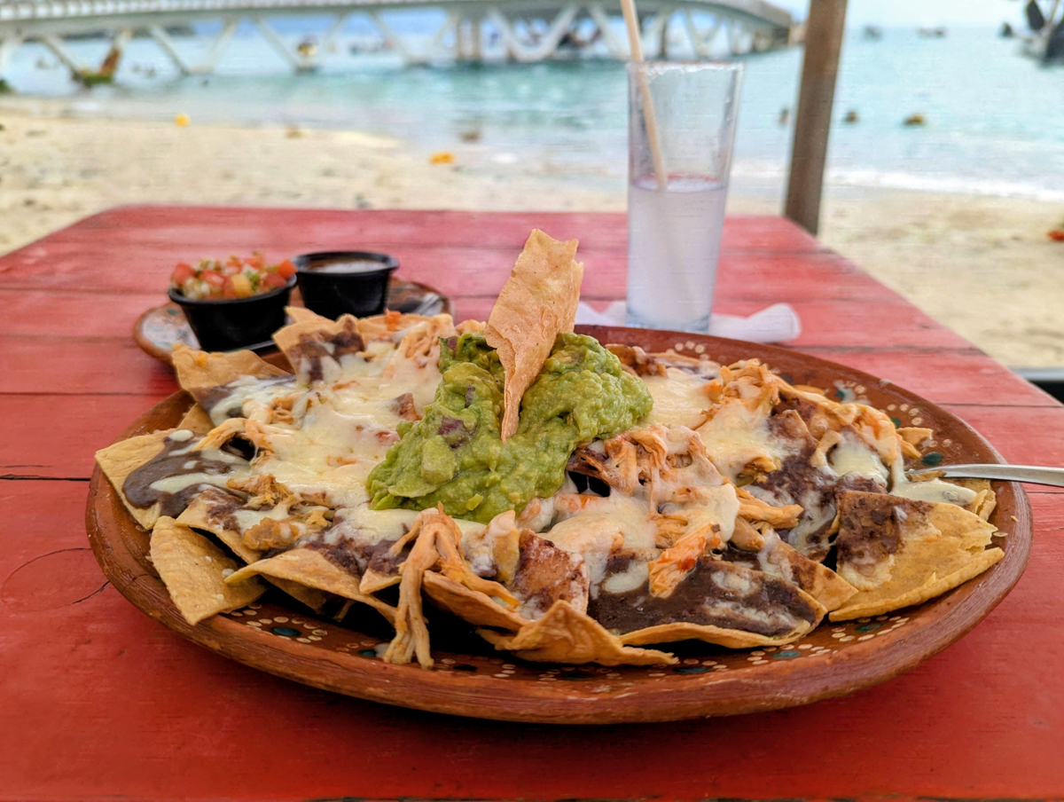 a plate of nachos at an outside table  on the beach at Cuates y Cuetos in Puerto 