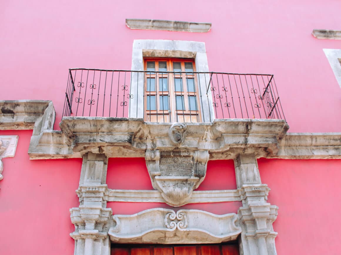 a brightly colored pink building in the historic center of Tepci
