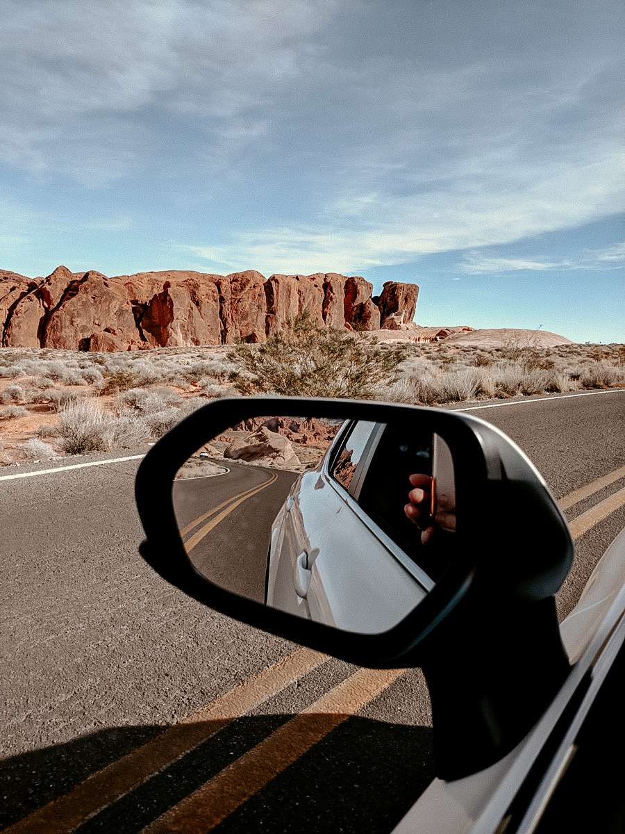 A rearview mirror of a car in the desert near the red rocks of Valley of Fire State Park
