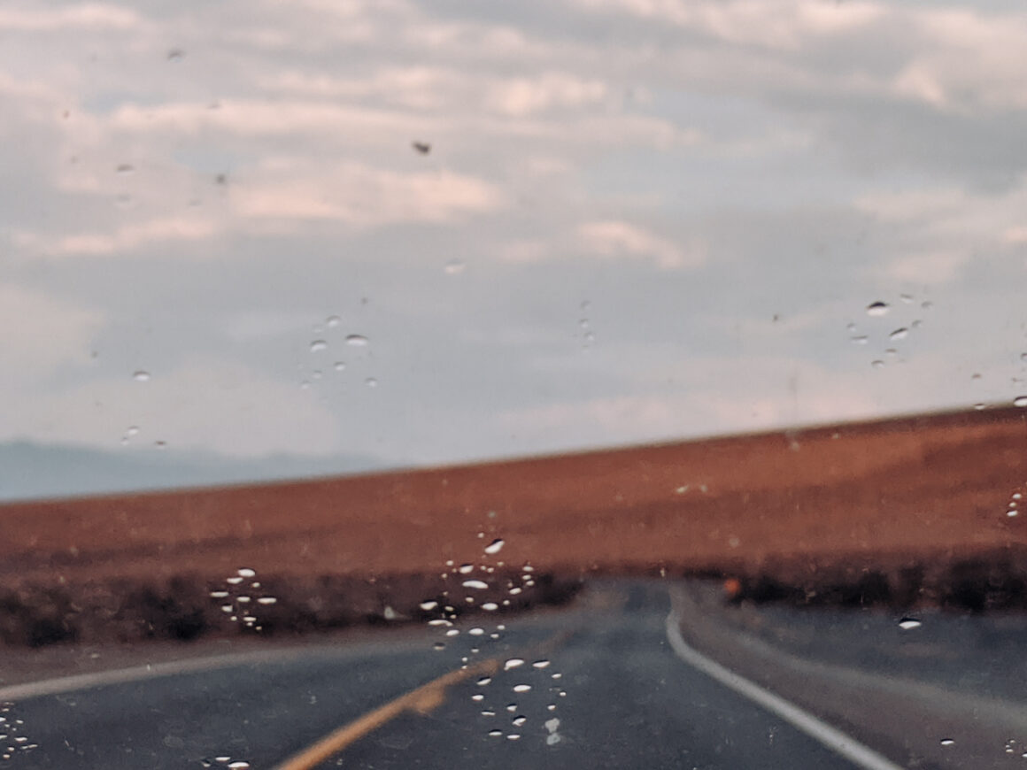 a car on the road with raindrops on the windshield, proof that one of the things you need to know about Death Valley National Park is that it does rain in the park