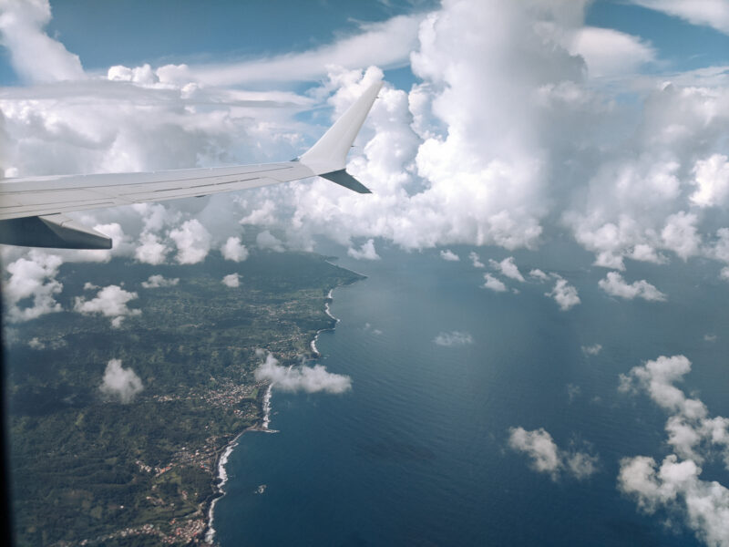 An island surrounded by blue water from above looking through an airplane window