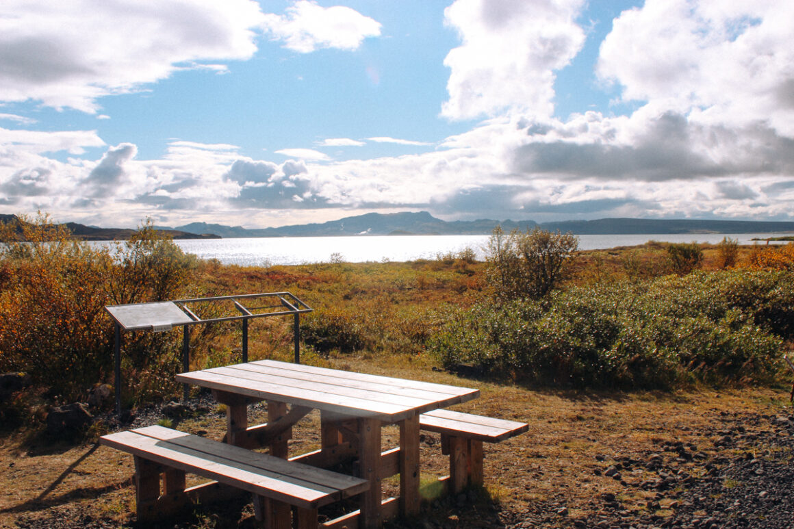 I picnic table along side a blue lake