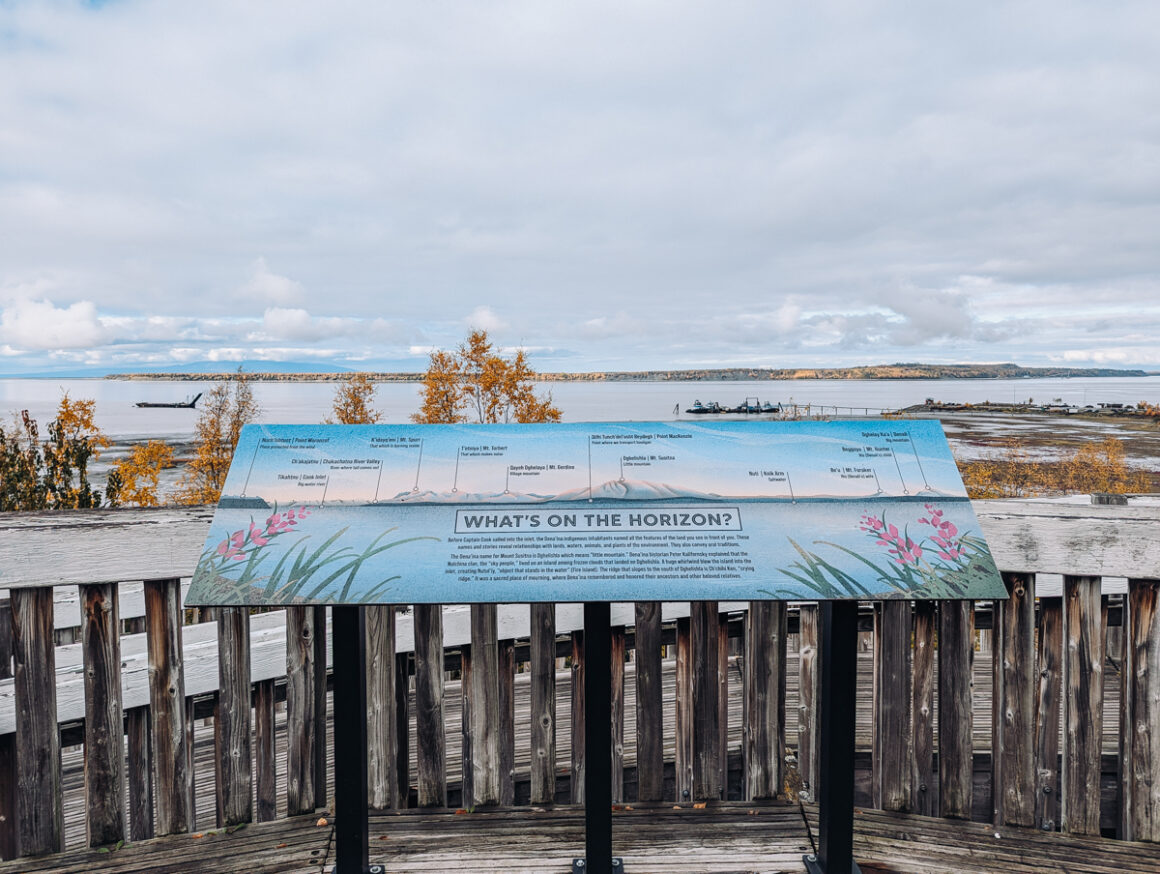 Mountains and water in the distance behind an educational sign in Anchorage, Alaska in September